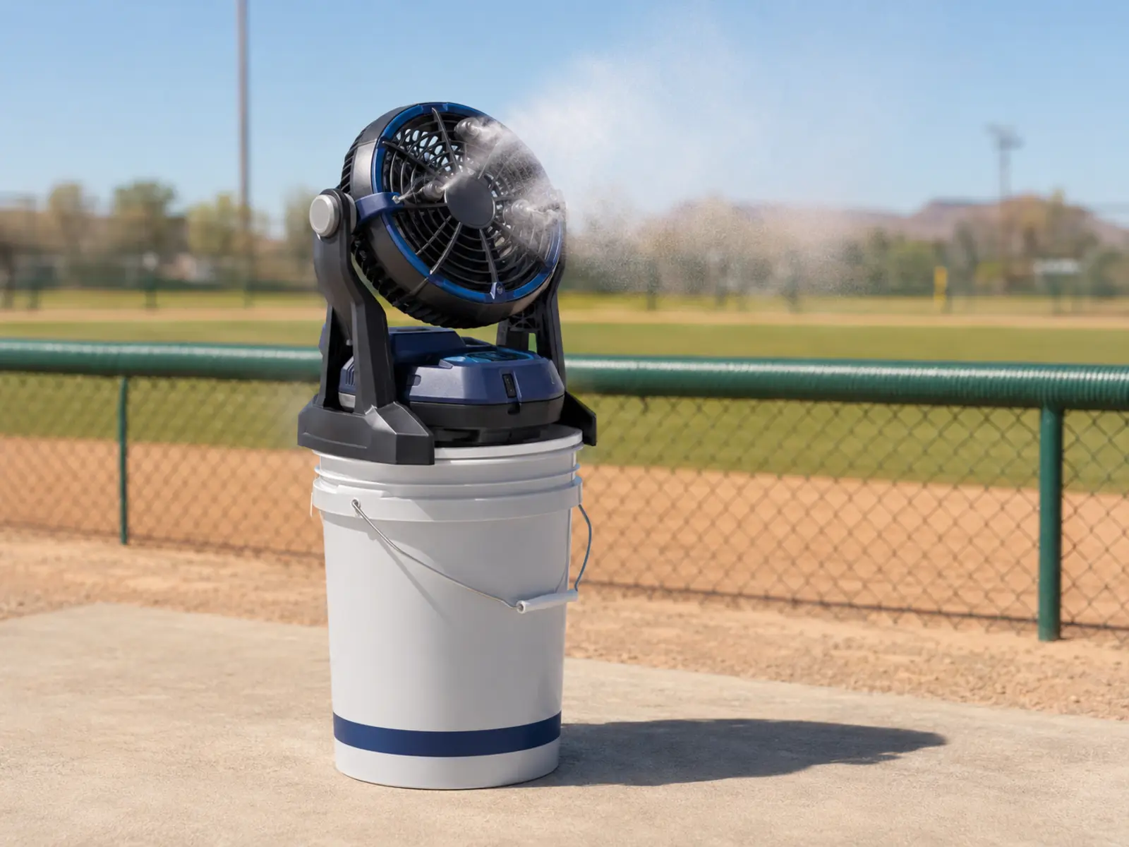 Portable misting fan set beside folding chairs along a Phoenix youth baseball sideline.