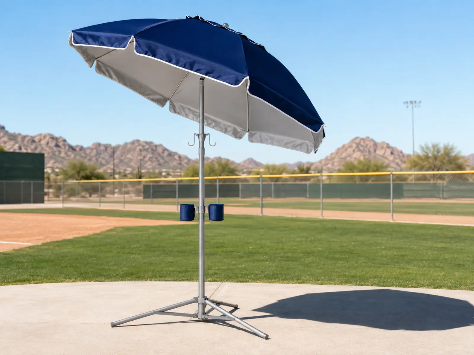 Freestanding shade umbrella covering spectator seating at a Phoenix youth baseball complex.